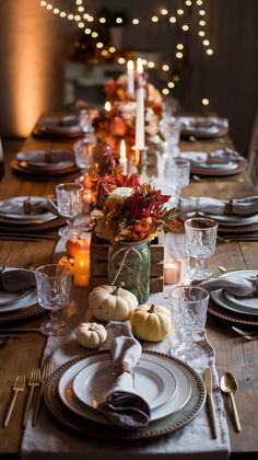 a table set for thanksgiving dinner with pumpkins and candles in the center, surrounded by other place settings