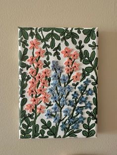 a white and blue flowered tile hanging on a wall next to a wooden table