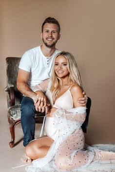 a man sitting next to a woman on top of a chair in front of a wall