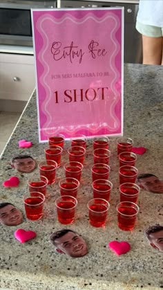 a table topped with lots of cups filled with red liquid and pink hearts on top of it