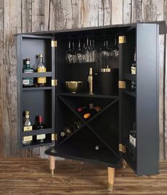 a black cabinet with wine glasses and liquor bottles in it on top of a wooden floor