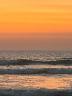 two surfers are riding the waves at sunset