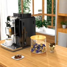 a coffee machine sitting on top of a wooden table next to a cup filled with chocolates