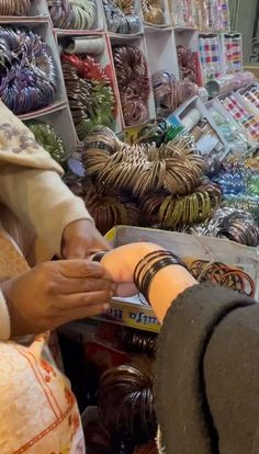 a woman standing in front of a display of bracelets