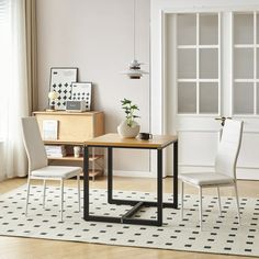 a dining room table with two chairs and a potted plant