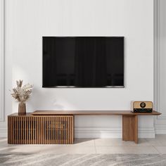 a flat screen tv mounted on the wall above a wooden table with a plant in it