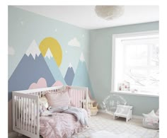 a baby's room with mountains painted on the wall and a crib in the foreground