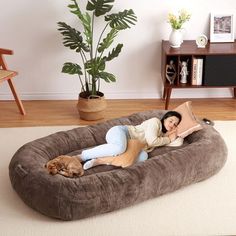 a woman laying on top of a dog bed in the middle of a living room