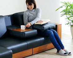 a woman sitting on a couch with a book and coffee cup in her hand while reading