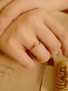 a close up of a person's hand with a ring on top of an open book