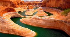 the water is green and blue in this canyon area with large cliffs on either side