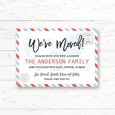 we're moved sign on a white wooden background with an envelope and red, blue, and gray stripes