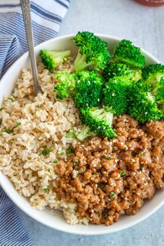 a bowl filled with rice, meat and broccoli on top of a table