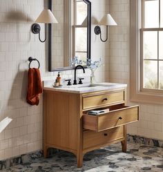 a bathroom vanity with two mirrors and lights on the wall next to it is decorated in black and white tiles