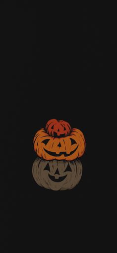 two pumpkins sitting on top of each other in the dark