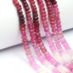 pink and red beads are lined up on a white surface