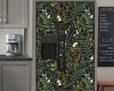 a kitchen with grey cabinets and white flowers on the wall next to a blackboard