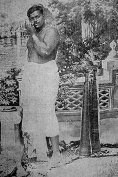 an old black and white photo of a man standing in front of a tree with his hands on his chin