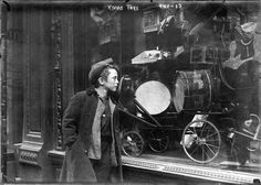 an old black and white photo of a man standing in front of a store window