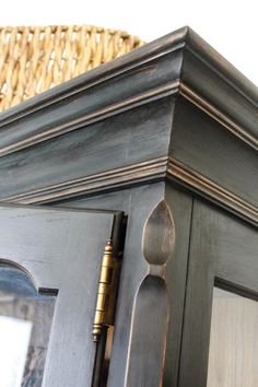 a close up of a wooden cabinet with a basket in the background