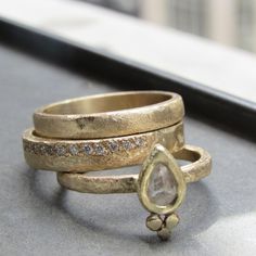 two gold rings sitting on top of each other next to a window sill with a diamond in the middle