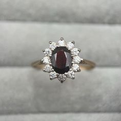 A rather glamorous vintage 9ct gold garnet & cz cocktail ring! This wonderful cluster ring features a striking, large oval-cut garnet, offering a deep red hue and captivating glow at the centre. Twelve dazzling cubic zirconia stones surround the garnet, offering a classic, regalesque design that really catches the eye! This lovely piece has been hallmarked by the Birmingham Assay Office and bears a maker's mark for 'HW'. It does not feature a date letter, but is likely from the late 1990s/early 2000s era. It weighs 2.2 grams and fits a UK size T (US size 9 1/2).  A complimentary ring box will be provided. About Second Sparkle: Second Sparkle is my little collection of history & sparkle! As a jeweller's daughter with a historian's heart, I'm passionate about tales of times gone by and the s 2000s Era, Cluster Ring, Ring Box, Cocktail Ring, Early 2000s, Cocktail Rings, Rings Statement, Deep Red, Makers Mark