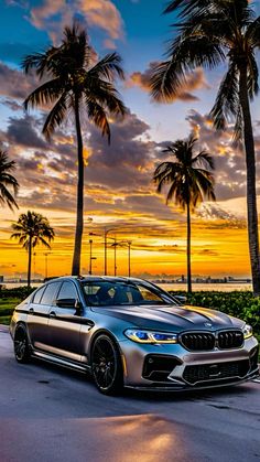 a silver car parked on the side of a road next to palm trees at sunset