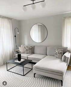 a living room filled with furniture and a round mirror on the wall above the couch