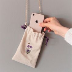 a hand holding an iphone in a bag with purple flowers on the front and side