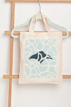 a tote bag hanging on a clothes rack with an orca in the background