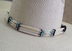 Be ready for compliments! This is a very UNIQUE Bone beaded hat band.  This  Cowboy hat band is very hard to miss.  2 colors beads with the white bone beads #1 has a light blue turquoise colored bead to add extra flare.  #2 has  black beads to compliment the White  bone beads.   Then it is trimmed with longer white bone beads and silver beads. The bead dividers are leather and the 3 piece silver buckle set is also attached with select supple leather.  It is uniquely DISTINCTIVE and very handsome White Beaded Hat Bands For Rodeo, White Beaded Hat Band For Rodeo, White Beaded Hat Bands For Festival, Adjustable Beaded White Hat Bands, Handmade White Headband Jewelry, Adjustable Beaded White Hat, Bohemian Beaded White Hat Bands, White Handmade Jewelry Headband, Handmade White Jewelry Headband