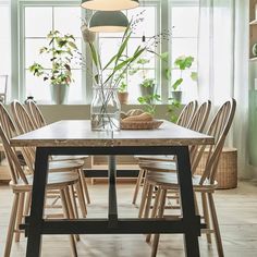 a dining room table with chairs around it and plants in the window sill behind it