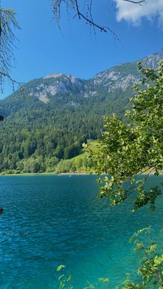 there is a boat that is sitting on the water in front of mountains and trees