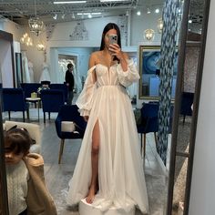 a woman taking a selfie in front of a mirror while wearing a white dress