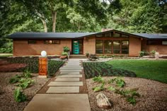 a house that is in the middle of some trees and grass with a walkway leading up to it