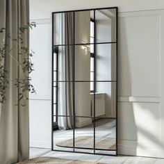 a large mirror sitting on top of a wooden floor next to a vase filled with flowers