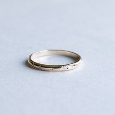 a white gold wedding ring with three diamonds on it's side, sitting on a plain surface