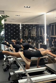 some people are doing exercises on treadmills in a room with mirrors and lights