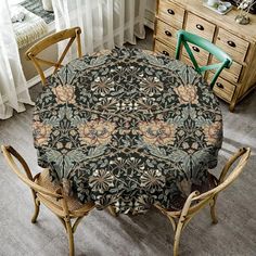 a dining room table covered with a black and gold floral print cloth next to two chairs