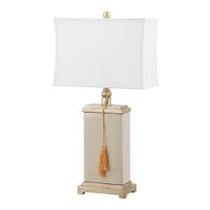 a lamp with a white shade on it and a yellow tassel hanging from the base