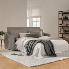 a large bed sitting on top of a wooden floor next to a book shelf filled with books