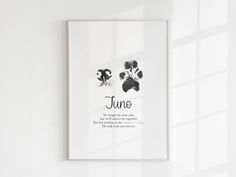 a white frame hanging on the wall above a black and white dog paw print that says june