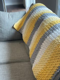 a crocheted yellow and gray pillow on a couch