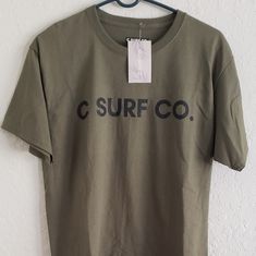 Size M C Surf T Shirt Brand New With Tag Dark Green In Color Casual Surfing T-shirt With Graphic Print, Surfing Graphic Tee Shirt With Crew Neck, Cotton Surfing Shirt With Letter Print, Graphic Tee Crew Neck Shirt For Surfing, Cotton Short Sleeve Surfing T-shirt, Short Sleeve Cotton T-shirt For Surfing, Cotton Short Sleeve T-shirt For Surfing, Green Casual Tops With Branding, Casual Green Shirt With Branding