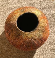 a brown and orange object sitting on top of a carpeted floor next to a black hole