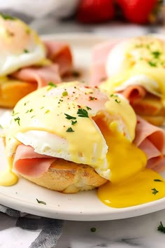 ham, eggs and hollandaise on english muffins with strawberries in the background