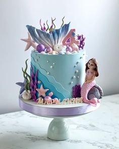 there is a cake decorated with mermaids and seashells