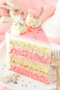 a slice of cake with pink frosting and sprinkles on a plate