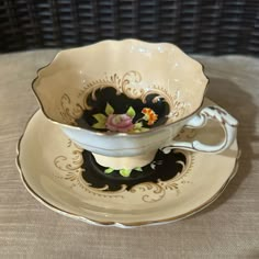 an antique tea cup and saucer with flowers on the rim, sitting on a table