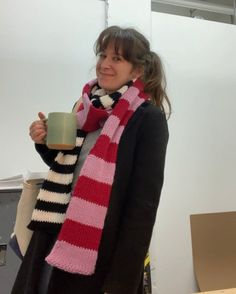 a woman wearing a scarf and holding a cup